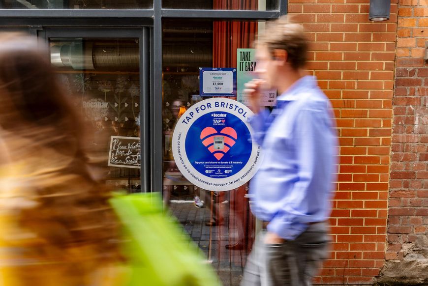 Blurred people walking, focus on sign for 'Tap for Bristol'